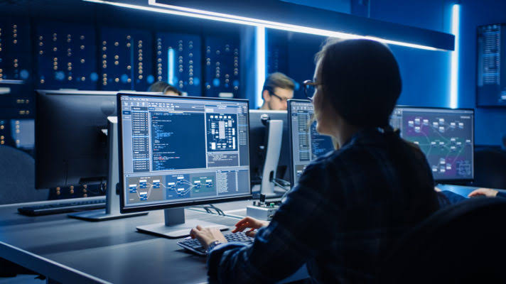 Engineers working across monitors in a development operations room